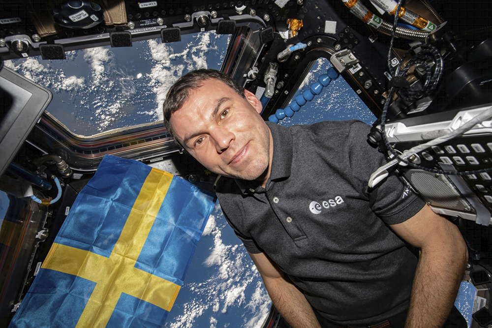 Marcus Wandt med svensk flagga i Cupolan på ISS. Foto: Rymdstyrelsen / Via TT