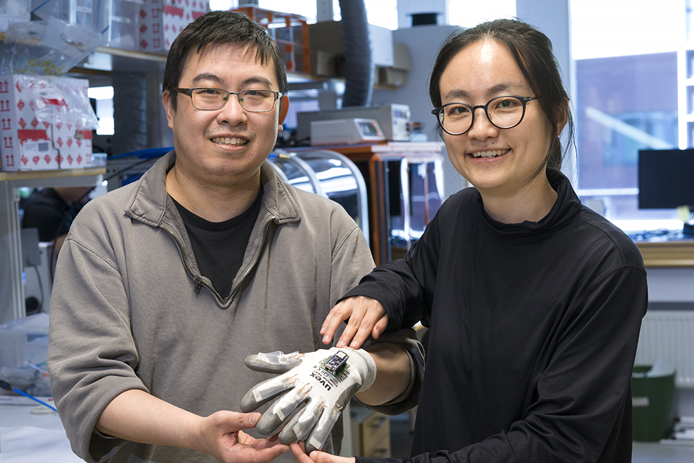 Jing Xu och Qi Lin har tillsammans tagit fram en handske som med AI-stöd ska styra en haptisk robot på distans. Foto: Göran Ekeberg